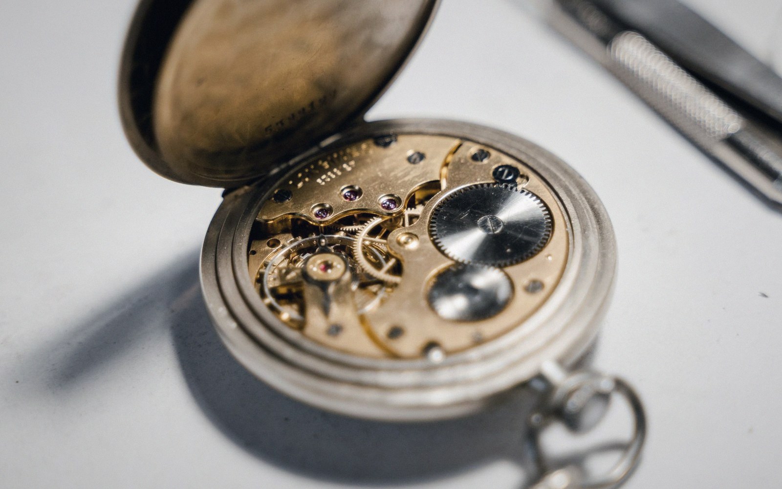 Open pocket watch case revealing gears and ruby jewel bearings in the movement